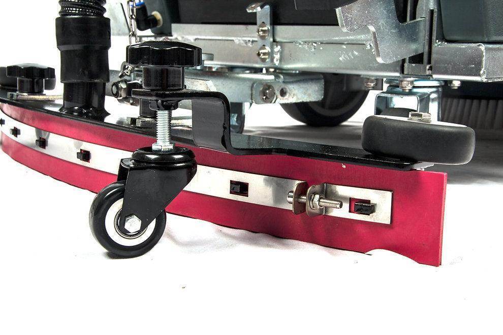 Close-up of 22-inch brush scrubbing path and wheels on battery-powered floor scrubber machine.