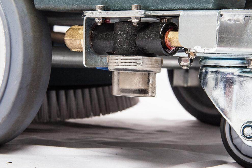 Close-up of 22-inch brush scrubbing path and wheels on battery-powered RT50+ floor scrubber machine.