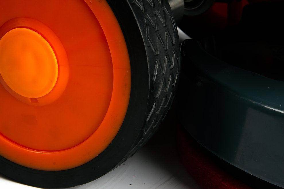 Close-up of the orange wheel of the RT50D Self-Propelled Floor Scrubber with black tire and part of the machine body.