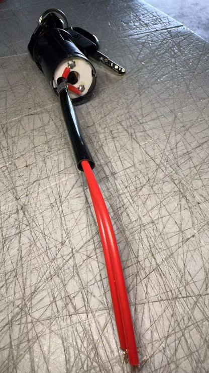 Lock and key set for floor scrubber machines with attached red wires on textured surface